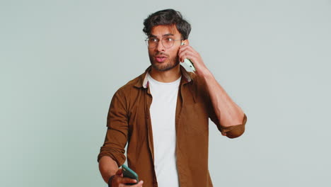 Irritated-stressed-business-man-talking-on-two-mobile-phones-having-conversation-conflict-quarrel