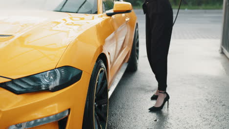 mujer lavando un coche deportivo amarillo