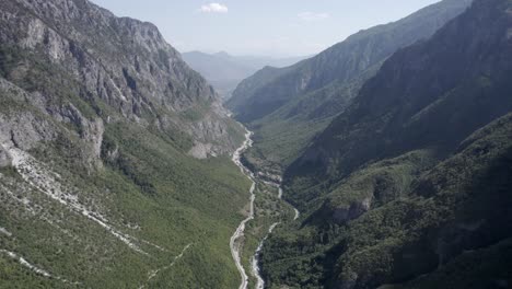 Frontales-Drohnenvideo,-Das-Sich-Zwischen-Den-Hügeln-Des-Valbone-Tals-Und-über-Die-Straße-Azem-Hajdari-Und-Den-Fluss-Bewegt