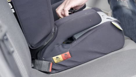 man installing a child safety car seat into an automobile