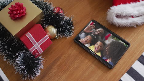 familia afroamericana sonriente en la videollamada de navidad en la tableta