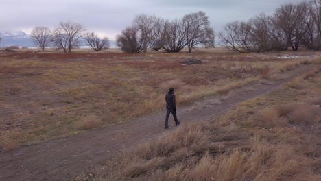 a man walks off the paved path towards a lake and mountians - panning and zooming