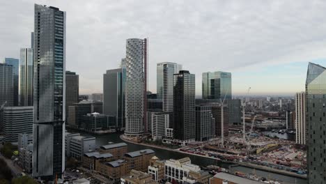 aerial trucking shot: cityscape with modern buildings and construction site with cranes of new architectures in canary wharf financial district in london