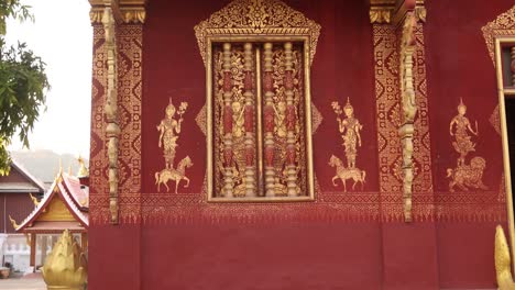 red and gold designs on exterior of buddhist temple in luang prabang, laos traveling southeast asia