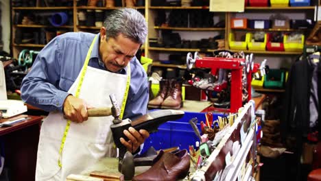 zapatero haciendo zapatos con un martillo