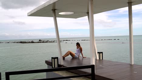 a woman sits on the quay and looking at the sea