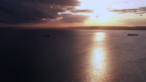 panorámica lenta a la derecha de un dron sobre coney island creek mirando hacia una puesta de sol dorada en una tarde nublada