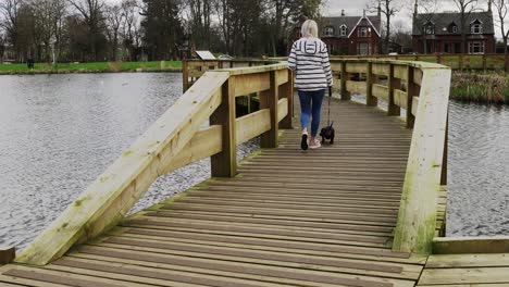 a woman walking her dachshund dog at the local park