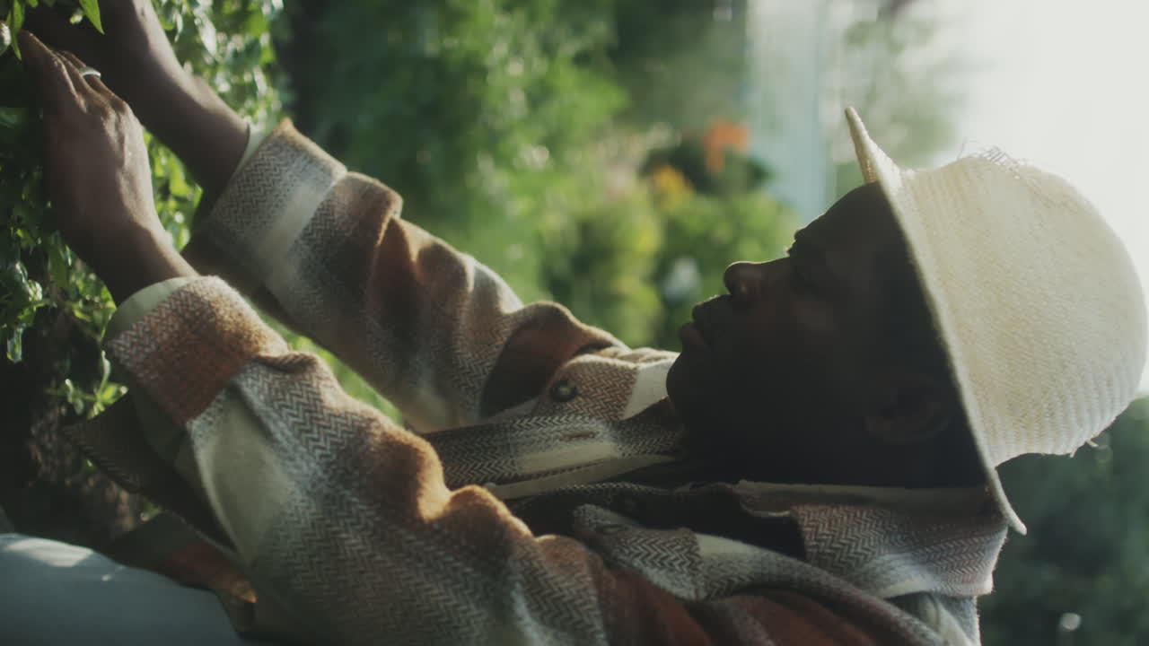 Man in a straw hat tending to plants in a garden