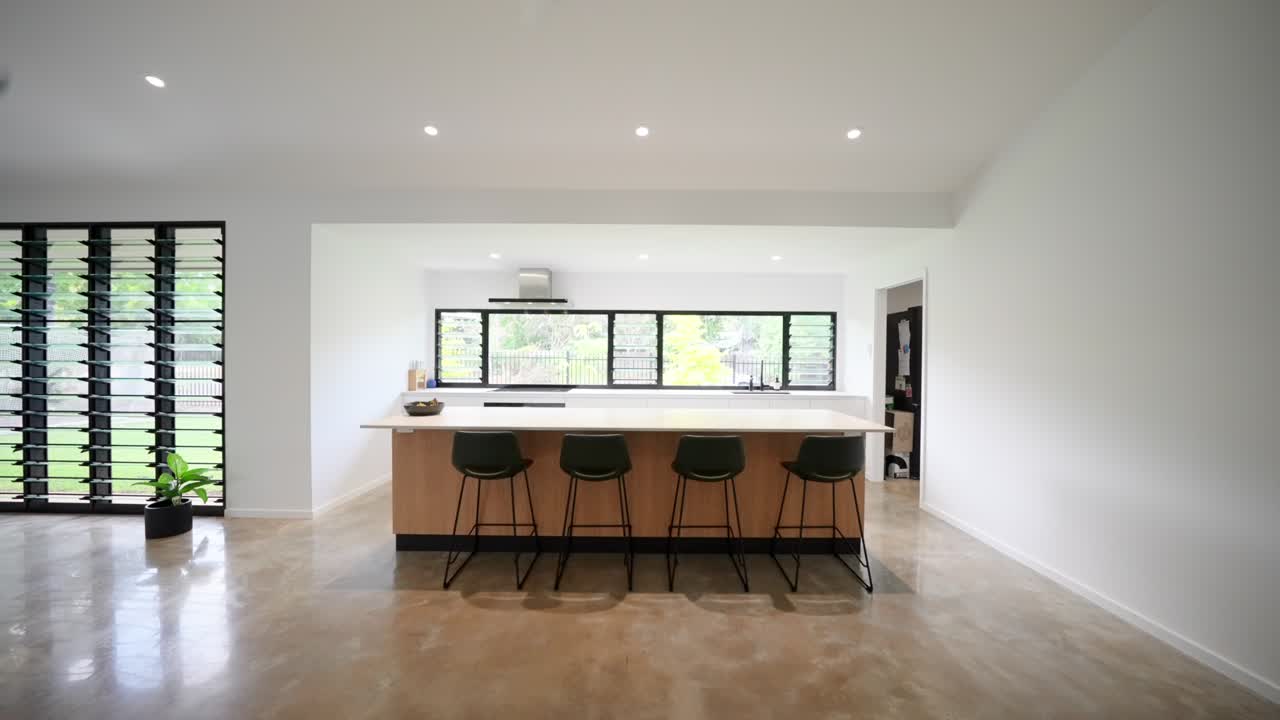 Open-plan kitchen in a modern tropical home with sleek cabinetry, island counter, and plenty of natural light