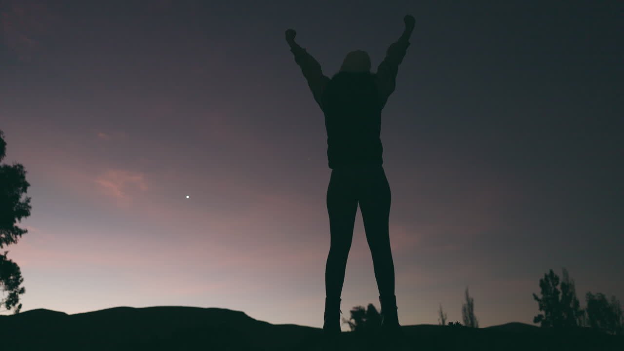 Donna, pugno alzato e silhouette sulla montagna