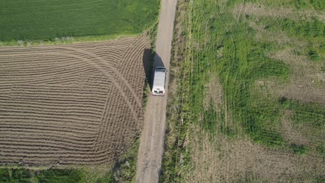 drone if following van car on the road through the natural agricultural fields during daytime and sunshine weather, location on the road in huelva, spain