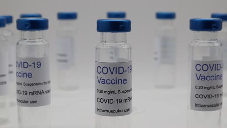 transparent glass vials with covid-19 vaccine label sars-cov2, on turntable, isolated on white background