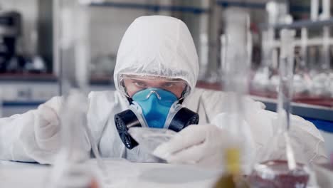 científico con traje protector trabaja en laboratorios modernos esparciendo polvo blanco