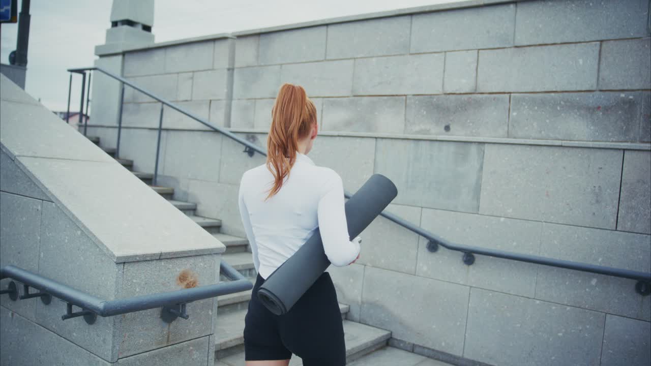 Woman with yoga mat walking up stairs