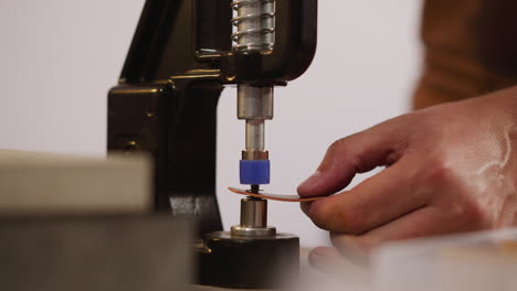 el maestro instala remaches en cuero con la máquina en el taller