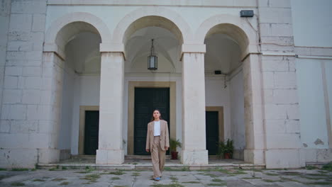 confident brunette walking old town district enjoying weekend trip. woman posing