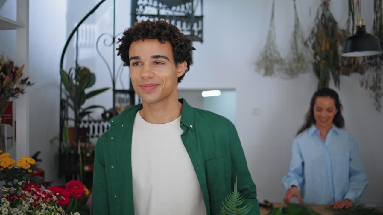 African man leave floristic store. Positive flower shop owner woman say goodbye.