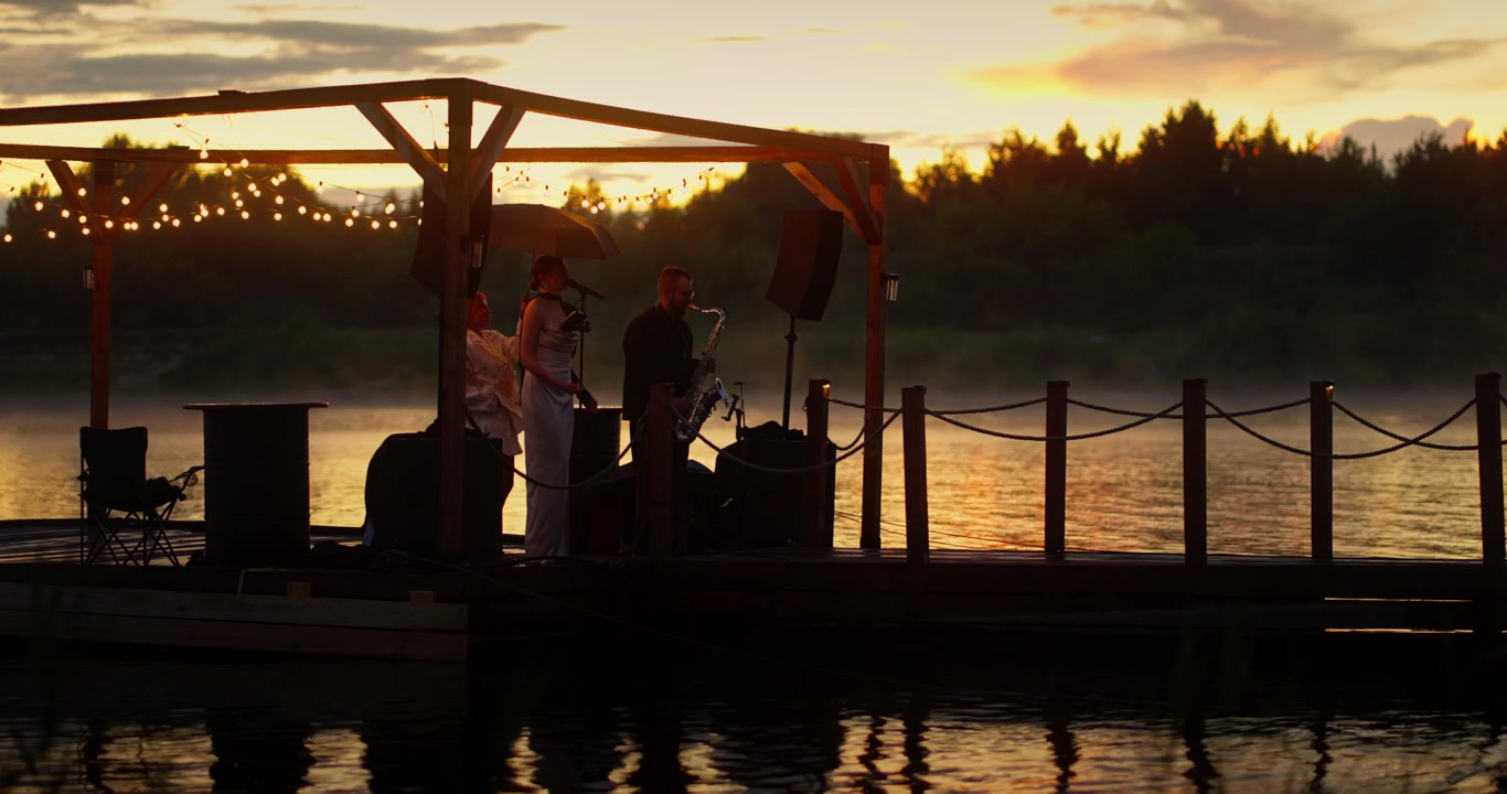 Musicisti che si esibiscono su un pontile galleggiante al tramonto
