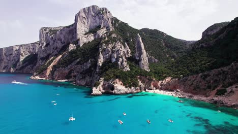 Aerial-view-of-tourist-boat-on-turquoise-sea-on-rock-coast,-Sardinia