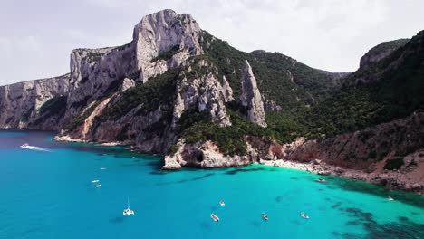 aerial view of tourist boat on turquoise sea on rock coast, sardinia