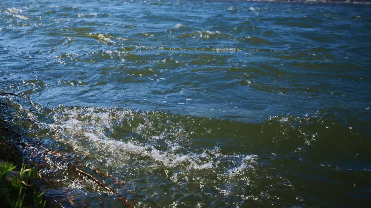 Close-up da superfície ondulante da água do rio com reflexos solares