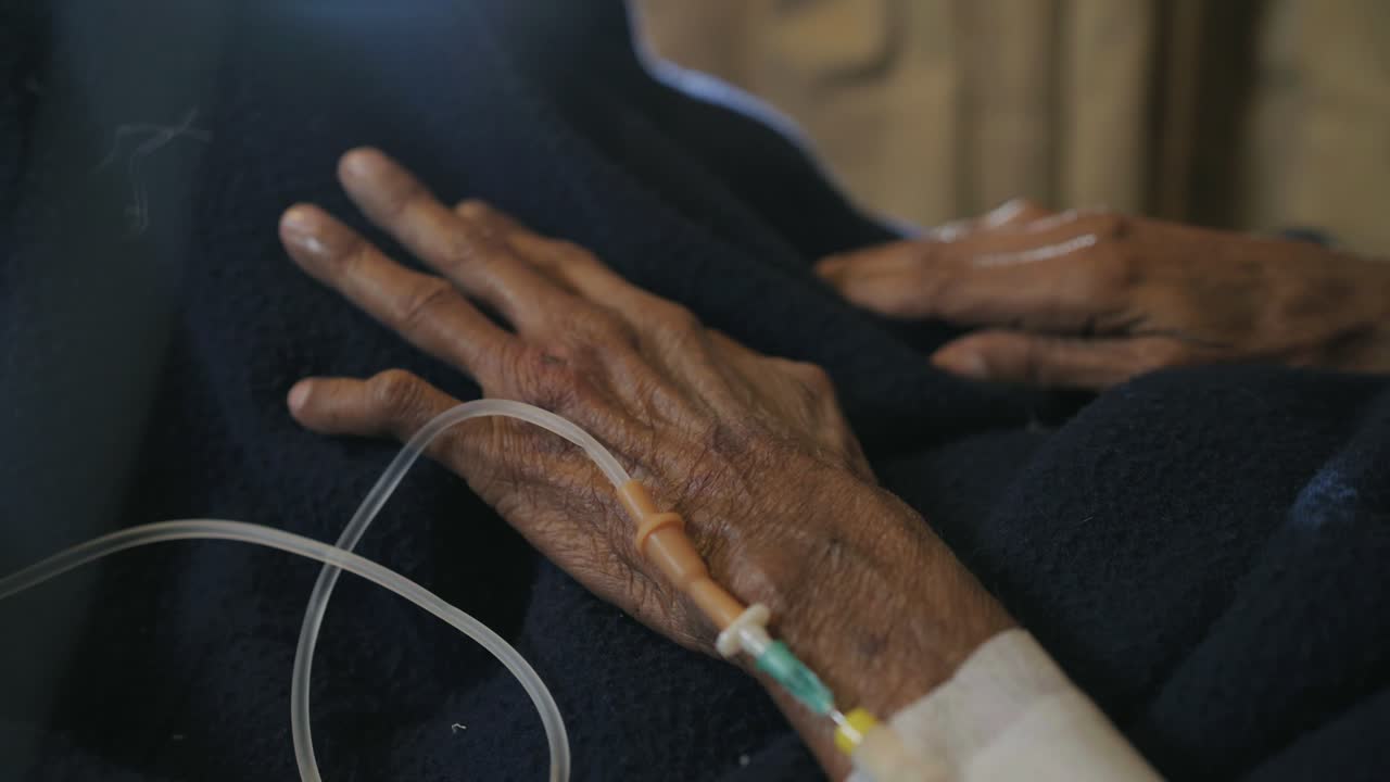 Closeup view of hand of an old man with IV drip inserted in a Pakistani hospital.