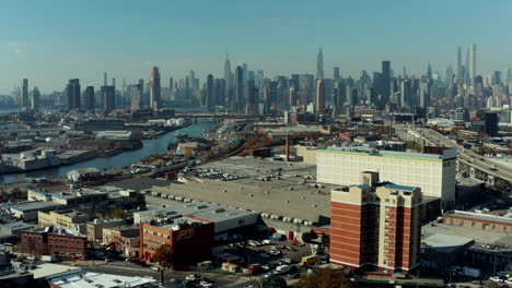 Aufsteigende-Aufnahmen-Aus-Der-Luft-Eines-Industriebezirks-Entlang-Der-Uferpromenade.-Moderne-Bürowolkenkratzer-Im-Hintergrund.-New-York-City,-Vereinigte-Staaten