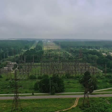 high voltage steel power station. flight over power transmission lines in green field countryside. electric tower line in a summer day. aerial view.