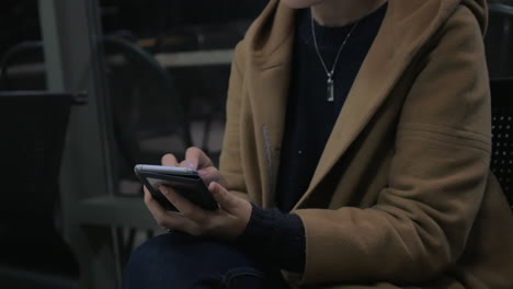 young girl sits on a chair holding a mobile phone