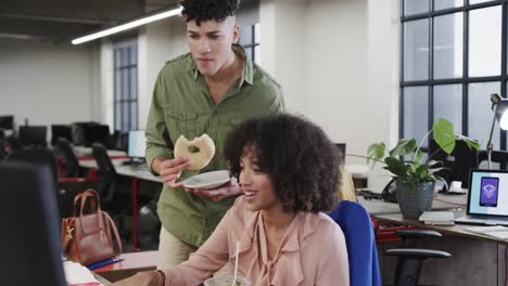 two happy diverse creative colleagues in discussion during lunch in casual office, slow motion