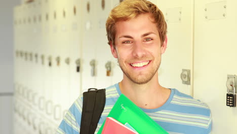 estudiante guapo apoyado en el casillero mirando a la cámara