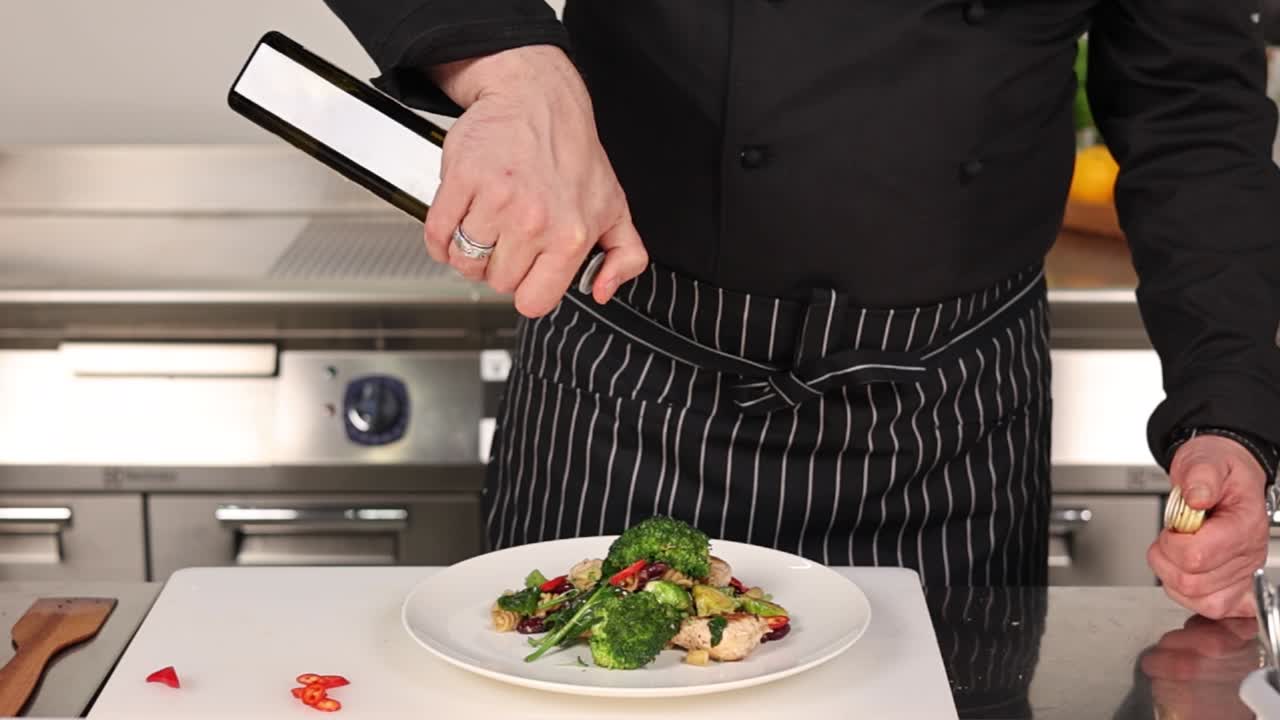 Chef Drizzling Olive Oil over a Healthy Chicken and Vegetable Dish