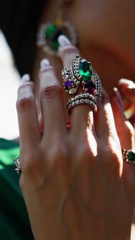 close-up of hand adorned with ornate emerald and gemstone rings
