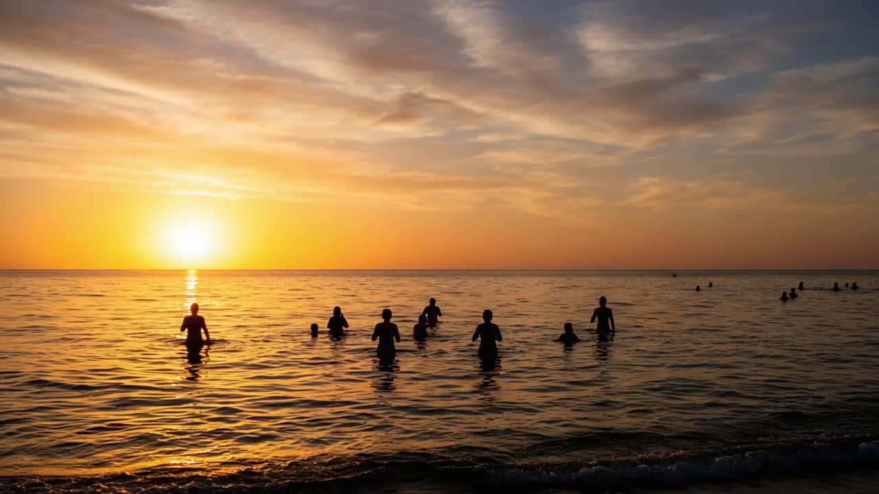 A tranquil sunset scene capturing silhouettes of people wading in the calm water, with vibrant hues of orange and gold filling the sky as day transitions to night