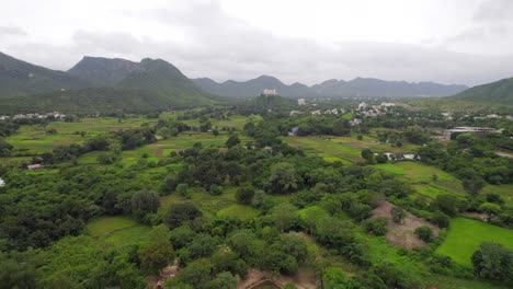 Flying-Over-Countryside-Fields-In-Udaipur-With-Sajjangarh-Monsoon-Palace-In-Distance-Background
