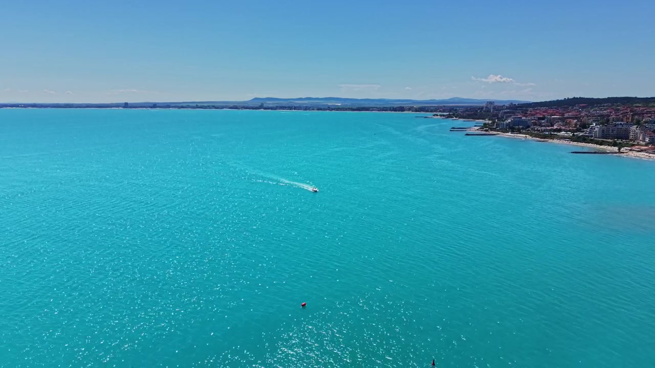 Giornata luminosa in spiaggia con una barca sull'acqua azzurra in lontananza.