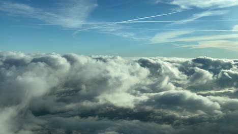 POV-Aufnahme-Eines-Piloten-Aus-Dem-Cockpit-Eines-Flugzeugs,-Das-Im-Goldenen-Moment-über-Einen-Himmel-Mit-Einigen-Flauschigen-Wolken-Fliegt,-Mit-Einigen-Kielwassern-In-Einem-Blauen-Himmel