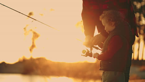 little boy is spending time with father or grandfather on river shore or lake coast in sunset