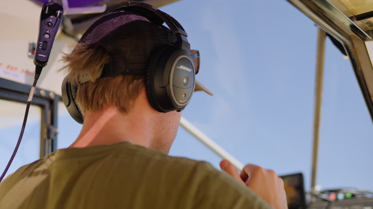 Uomo che indossa cuffie da aviatore nella cabina di pilotaggio di un aereo