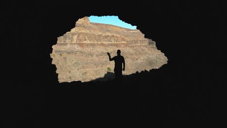 Silhouette of a man with a drone in his hand inside a cave