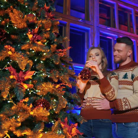 young happy woman is decorating a christmas tree with her husband. young couple is preparing for christmas and winter holidays. christmas spirit video. happy holidays