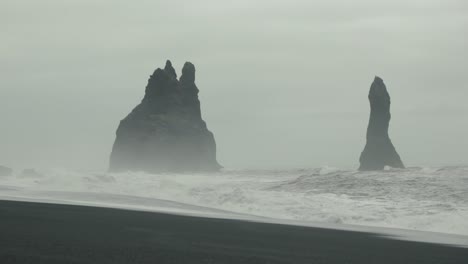 waves crash on a black sand beach in iceland