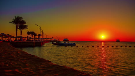 brilliant red sunrise over the red sea as luxury yachts come to the dock - time lapse