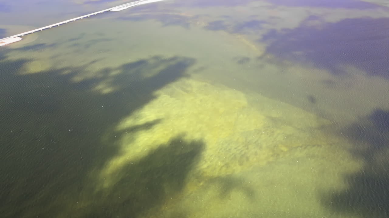 Ripresa aerea cinematografica ad alta quota da 70mm che esegue lentamente una panoramica verso l'alto dall'alto dell'ingresso di San Carlos Bay, la Sanibel Causeway, che collega l'isola di Sanibel con Fort Myers nel sud-ovest della Florida