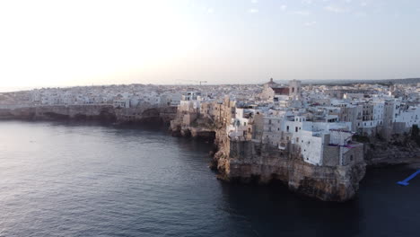 Edificios-Frente-Al-Mar-En-Acantilados-En-Polignano-A-Mare-En-Puglia,-Italia-Con-Vistas-A-La-Rampa-De-Salto-De-Acantilados-En-El-Borde