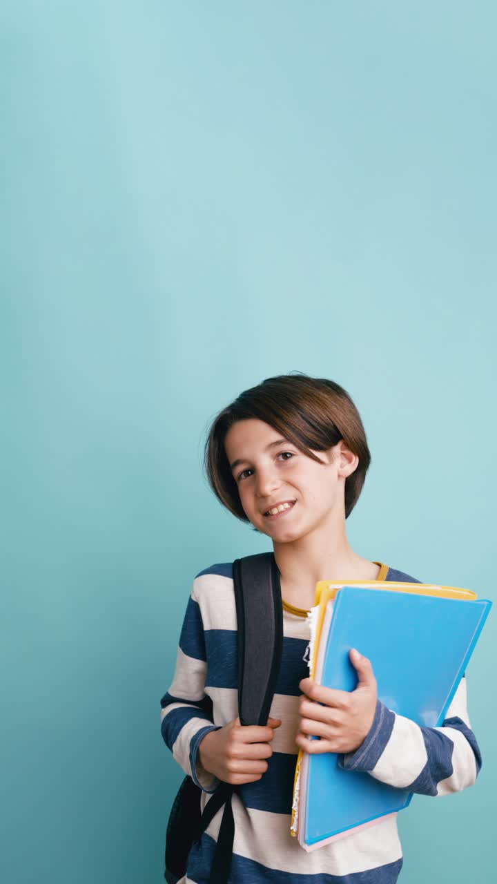 Joven estudiante feliz con mochila y carpetas sonriendo a la cámara