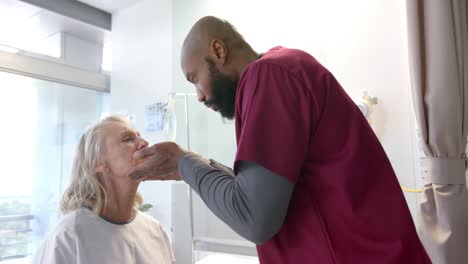 African-american-male-doctor-examining-face-of-caucasian-female-patient-at-hospital