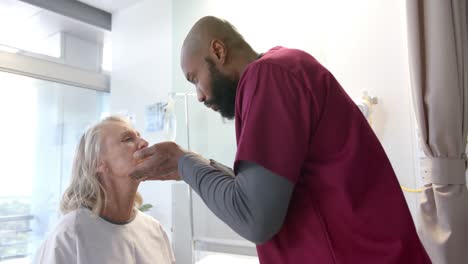 médico afroamericano examinando la cara de una paciente caucásica en el hospital