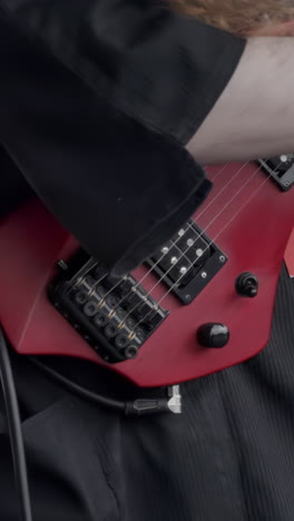 musician playing a red electric guitar